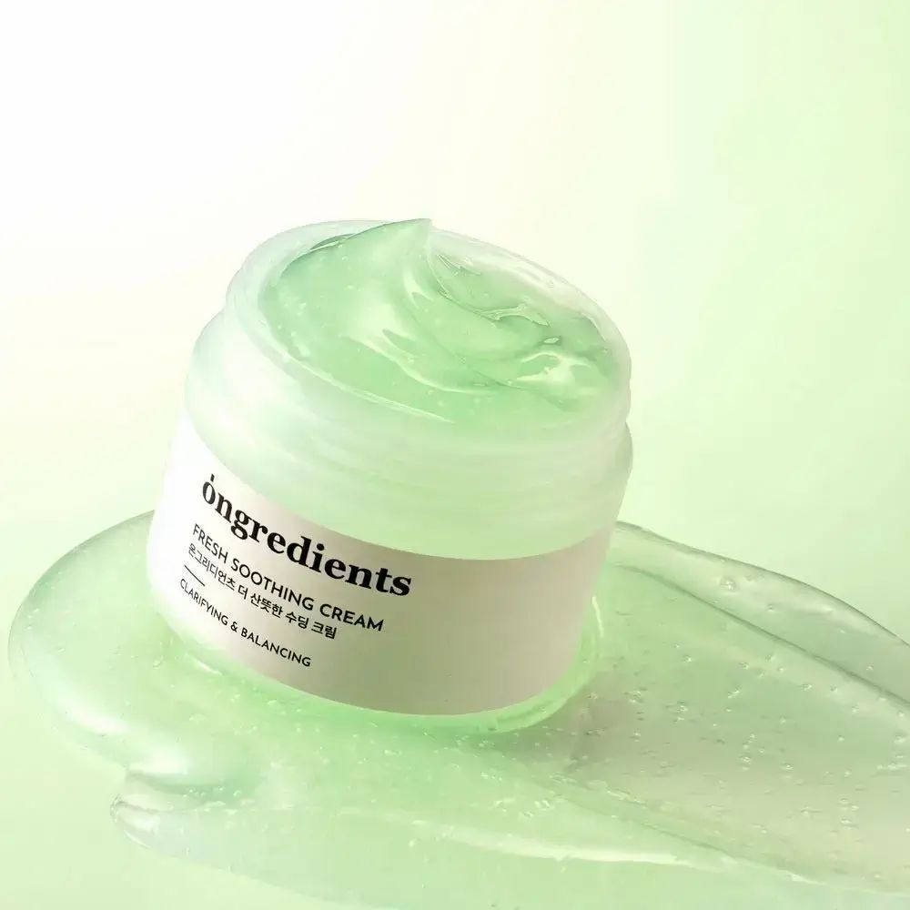 Vasetto di gel verde. Scritta: ōngredients, Fresh Soothing Cream. Testo in coreano. Gel sparso su una superficie verde.