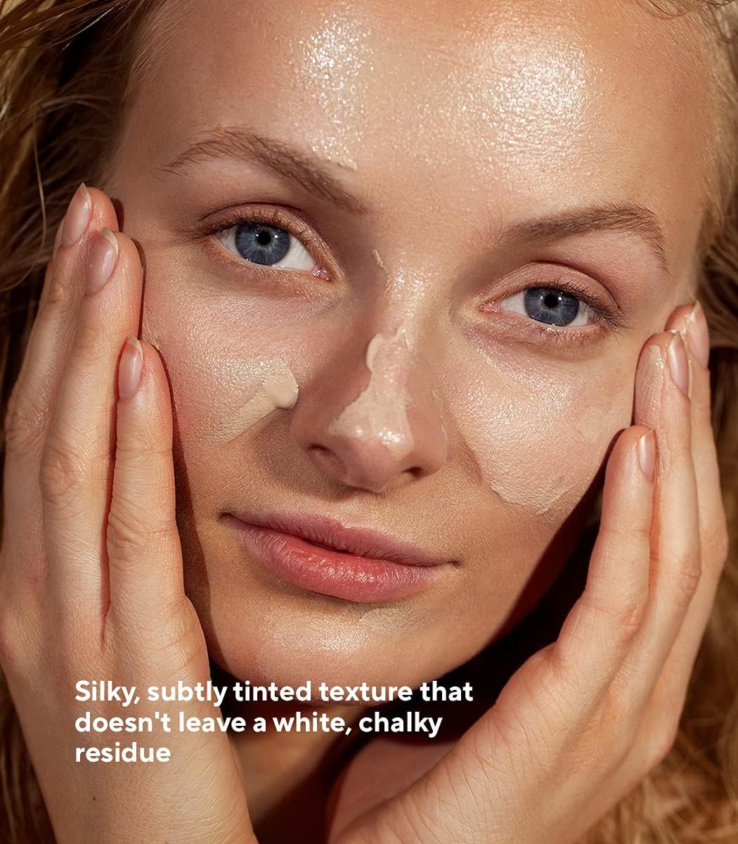 Donna con crema solare sul viso. Testo: Texture setosa, leggermente colorata, che non lascia residui bianchi e gessosi.