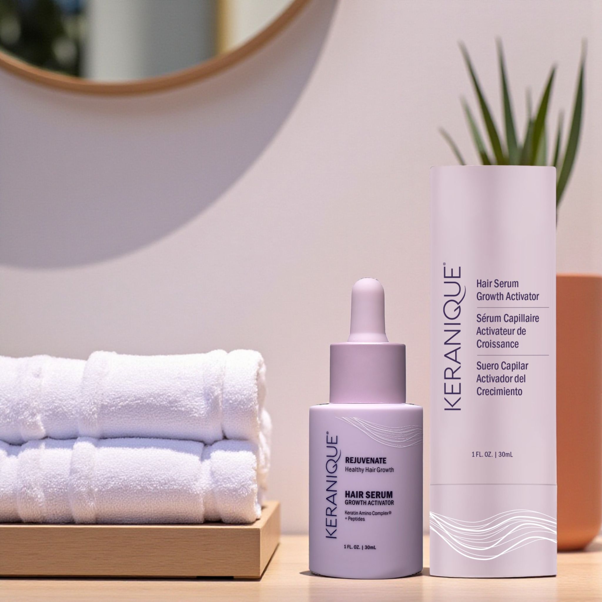 Flacone e flacone di siero. Scritta: KERANIQUE, Hair Serum Growth Activator, 1 fl. oz. | 30ml. Accanto, asciugamani.