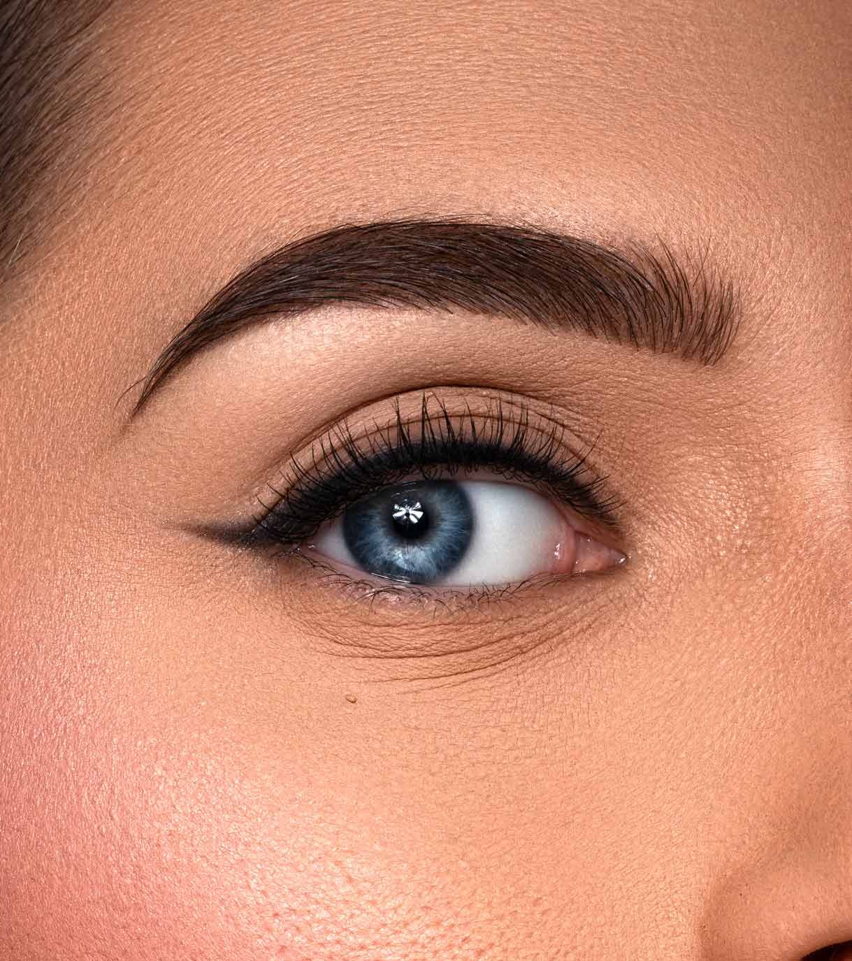 Primo piano di un occhio blu con eyeliner nero e ciglia folte.