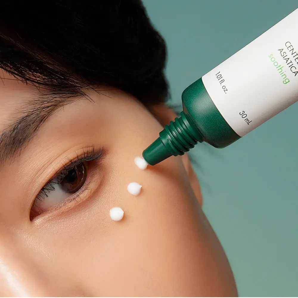 Primo piano di un occhio. La crema viene applicata sulla pelle da un tubetto. Testo: Centella Asiatica, soothing.