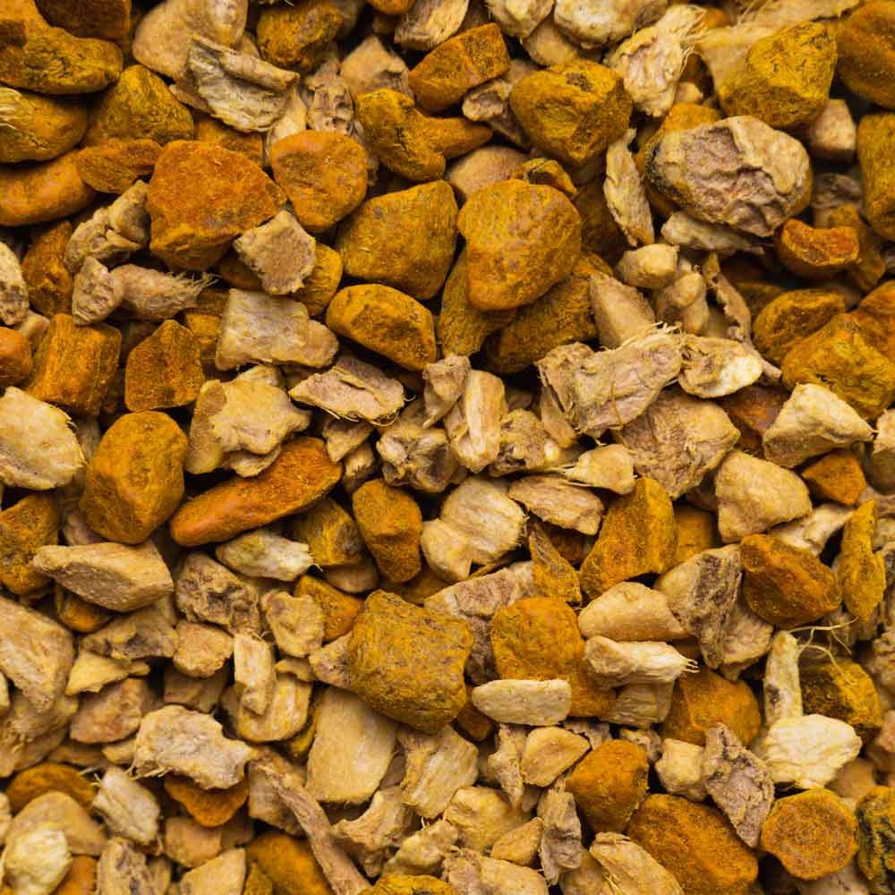 Primo piano di pezzi essiccati di curcuma e zenzero. Diverse dimensioni e colori, dal marrone chiaro all'arancione-giallo.