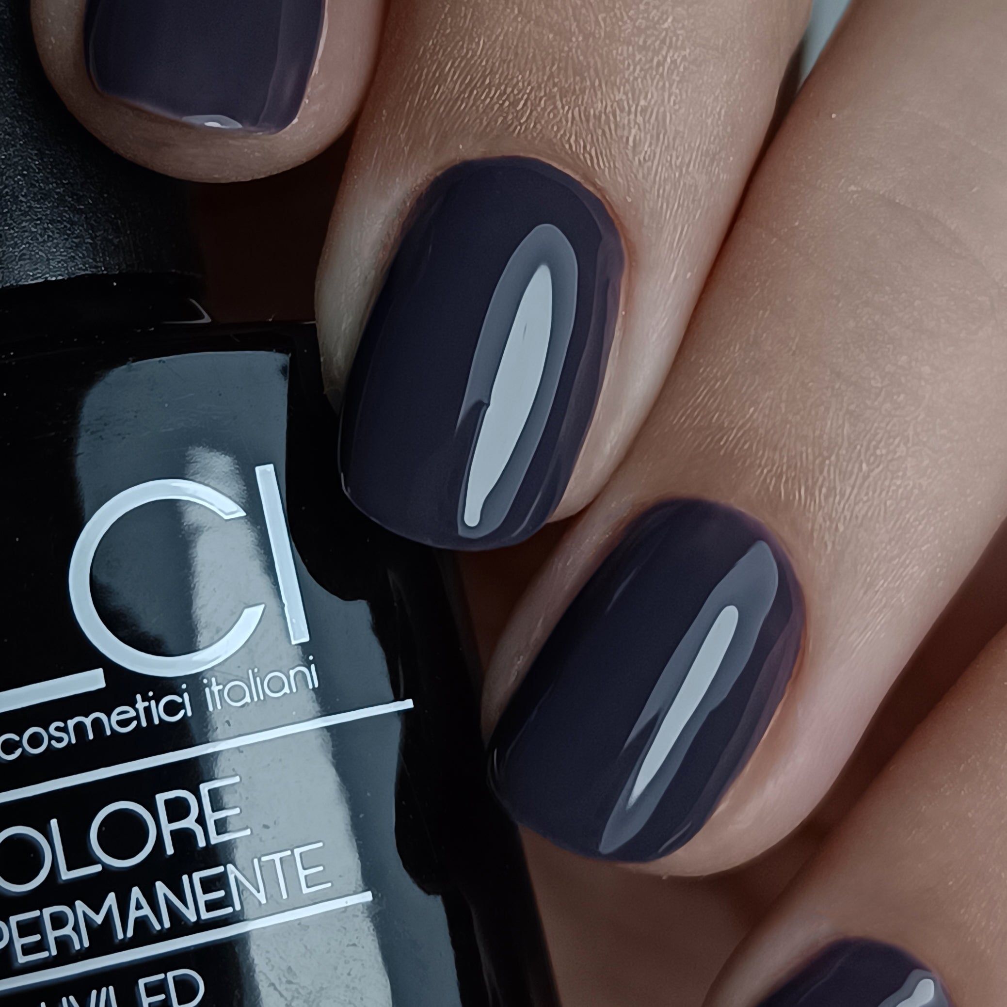 Mano con unghie smaltate di grigio. Flacone parzialmente visibile. Scritta: LCI, Colore Semipermanente, UVLED.