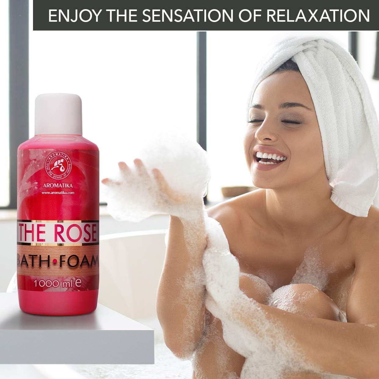 Flacone rosa AROMATIKA THE ROSE BATH FOAM. Donna con schiuma in mano, sorridente. Vasca da bagno sullo sfondo.