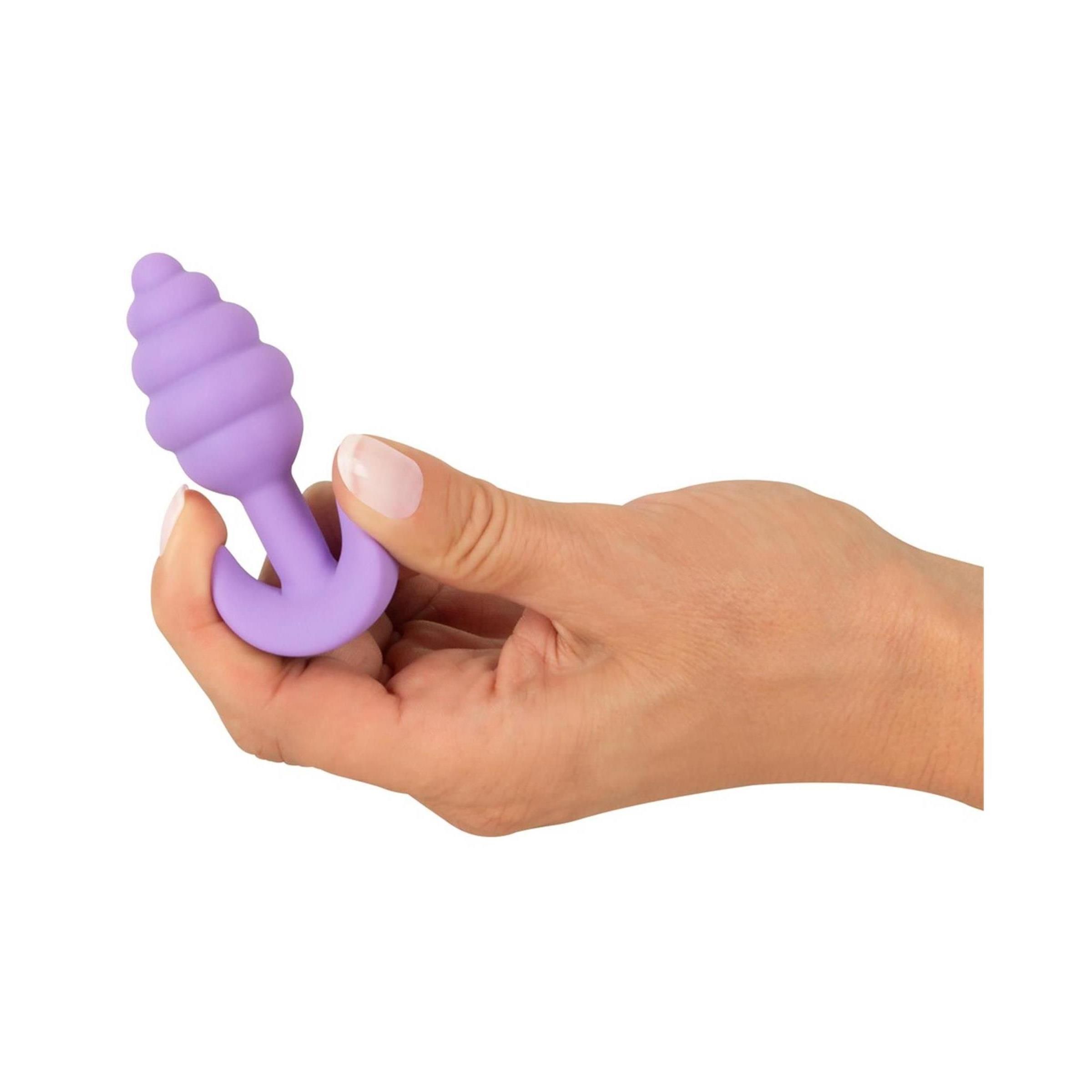Mano che tiene un plug anale viola, punta scanalata, base a T.