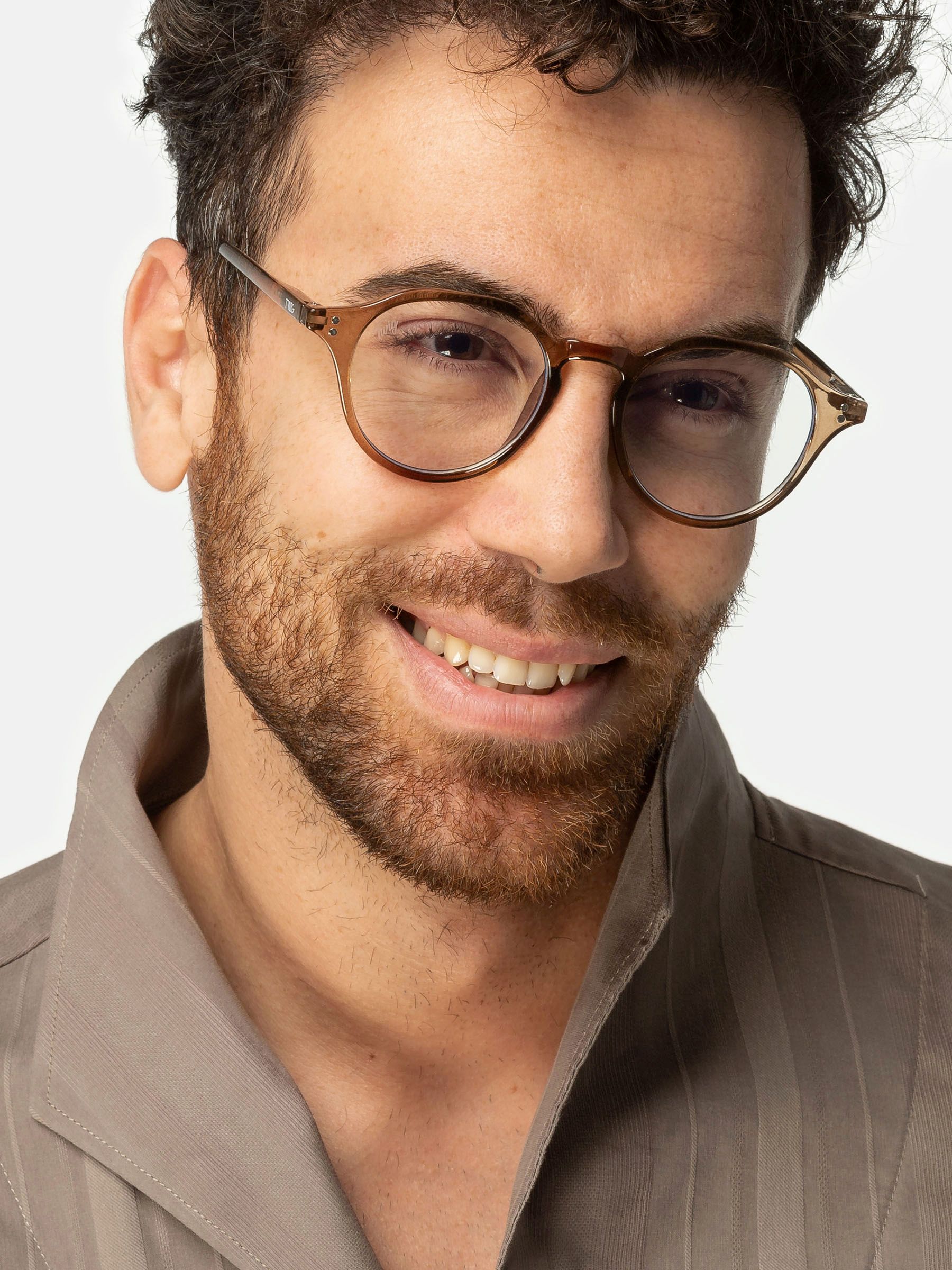 Uomo con occhiali Twig marroni. Montatura rotonda, lenti chiare. Sorride. Camicia beige.