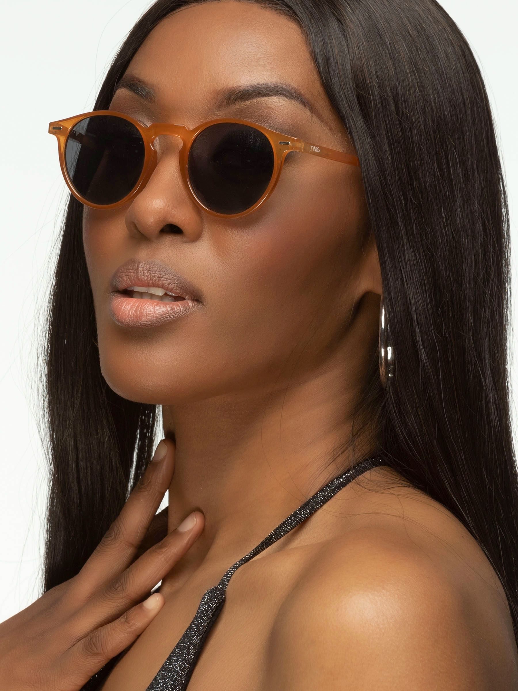 Donna con occhiali da sole marroni e lenti scure. Primo piano.