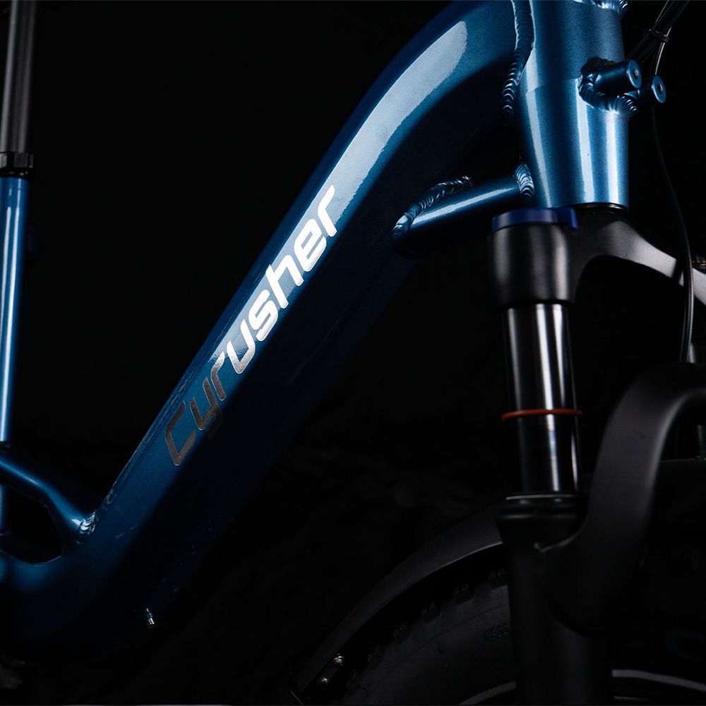 Primo piano del telaio di una e-bike blu. Logo CYRUSHER in bianco. Sospensione anteriore.