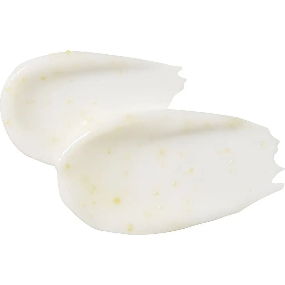 Due strisce di crema color crema su sfondo bianco. La consistenza è liscia con piccole particelle gialle.