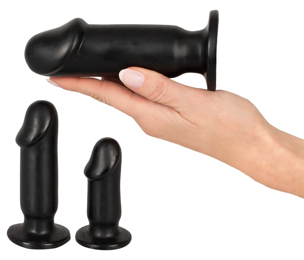 Tre plug anali neri. Un plug è tenuto in mano. Gli altri due sono accanto. Forma cilindrica con punta arrotondata.