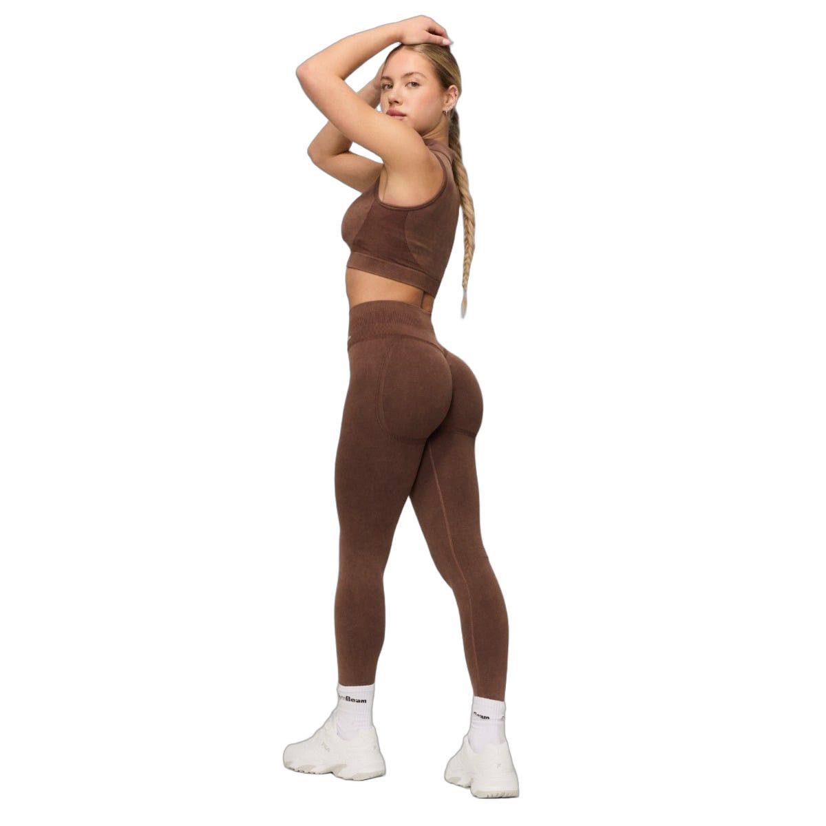 Vista laterale di una donna con leggings marroni senza cuciture a vita alta e top abbinato.