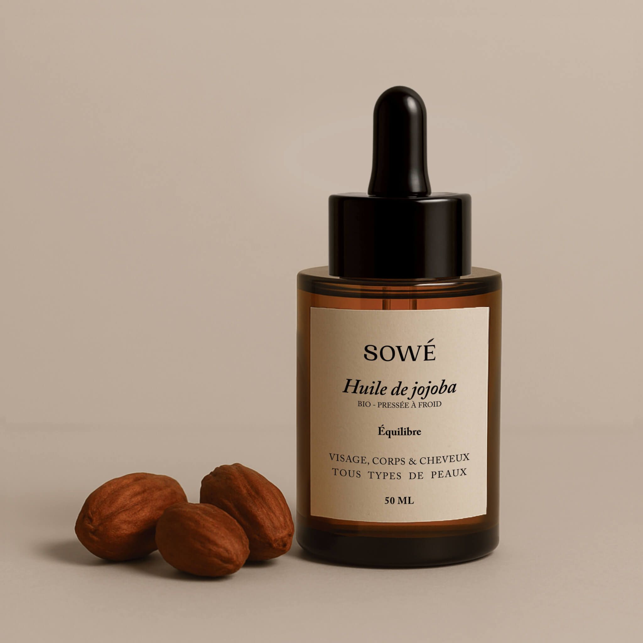 Flacone di vetro marrone con contagocce. Etichetta SOWÉ, Huile de jojoba. 3 semi accanto.