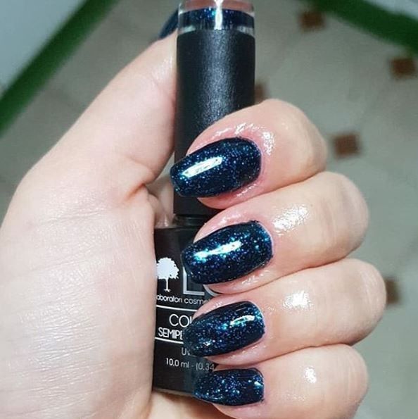 Mano con unghie smaltate di blu. Flacone di smalto con scritta: LCI Laboratori cosmetici italiani, Colore Semipermanente, UVLED 10,0 ml.