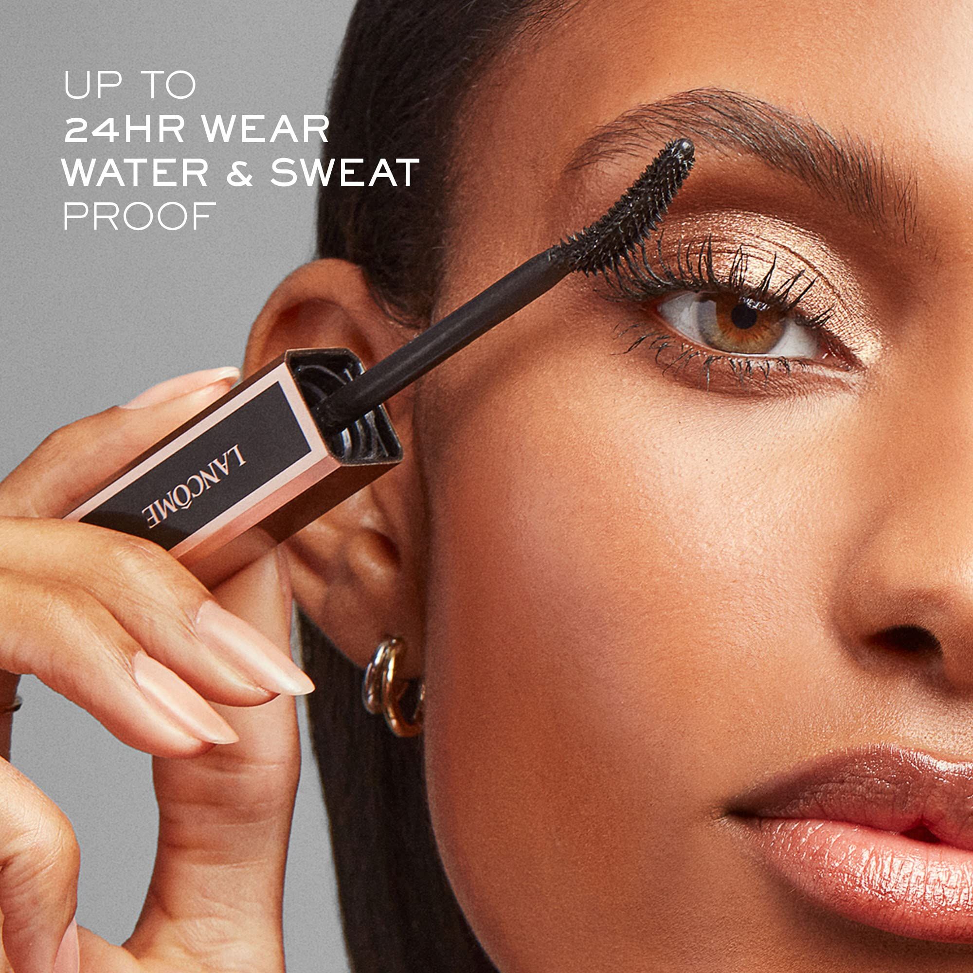 Donna applica mascara. Testo: "UP TO 24HR WEAR WATER & SWEAT PROOF". Tubo "LANCÔME".