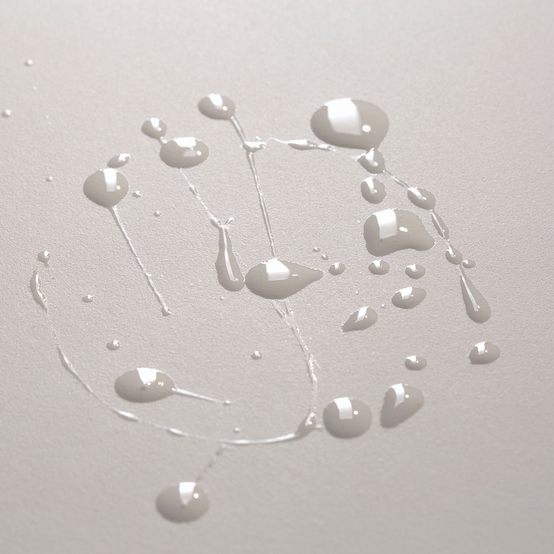 Gocce di liquido chiaro su sfondo neutro.