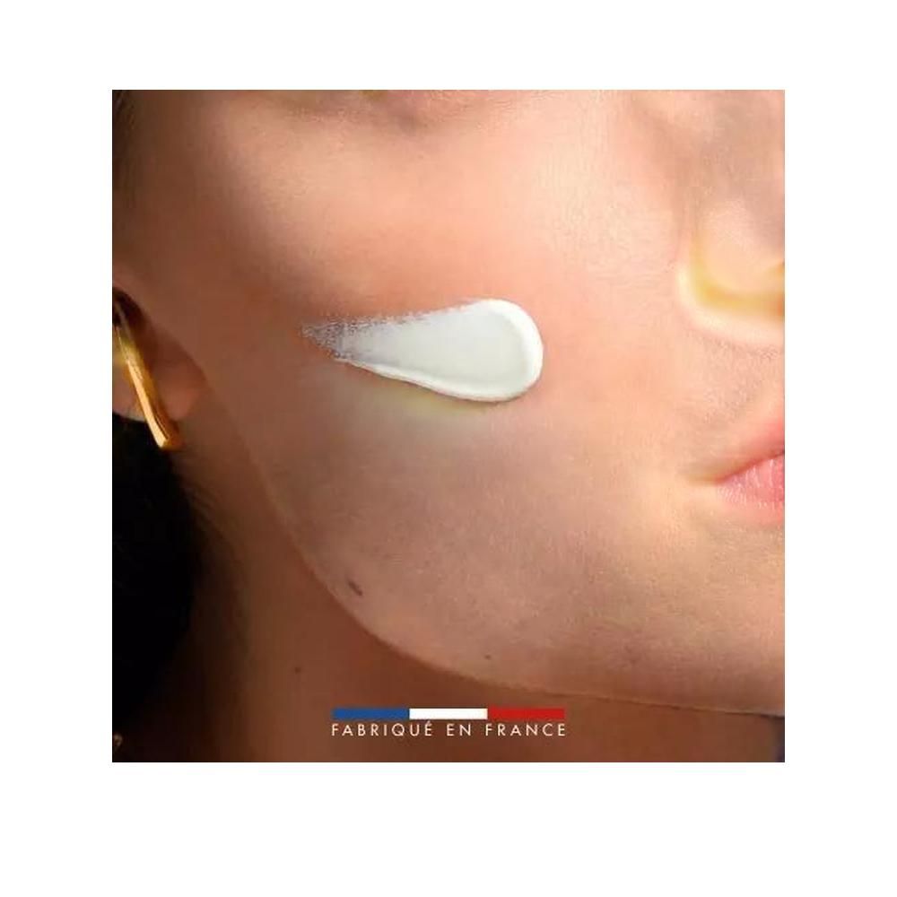 Primo piano di un viso. Sulla pelle è visibile una traccia di crema. In basso: Fabriqué en France.