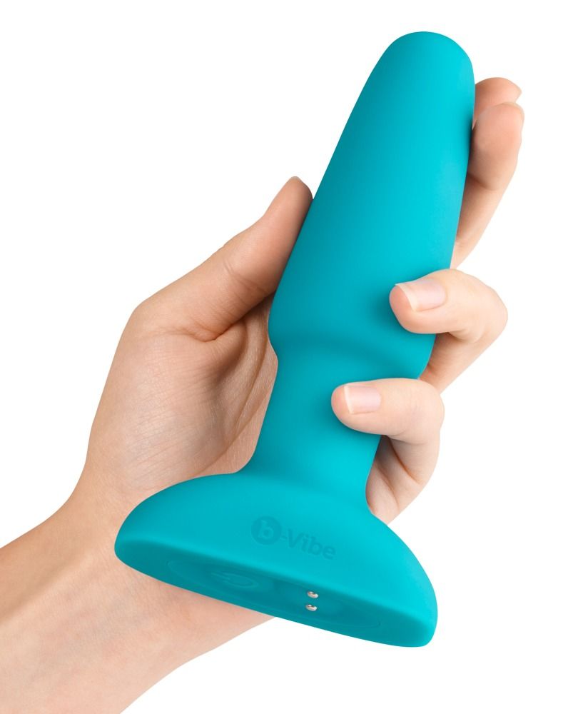 Vibratore anale turchese tenuto in una mano. Logo B-vibe.