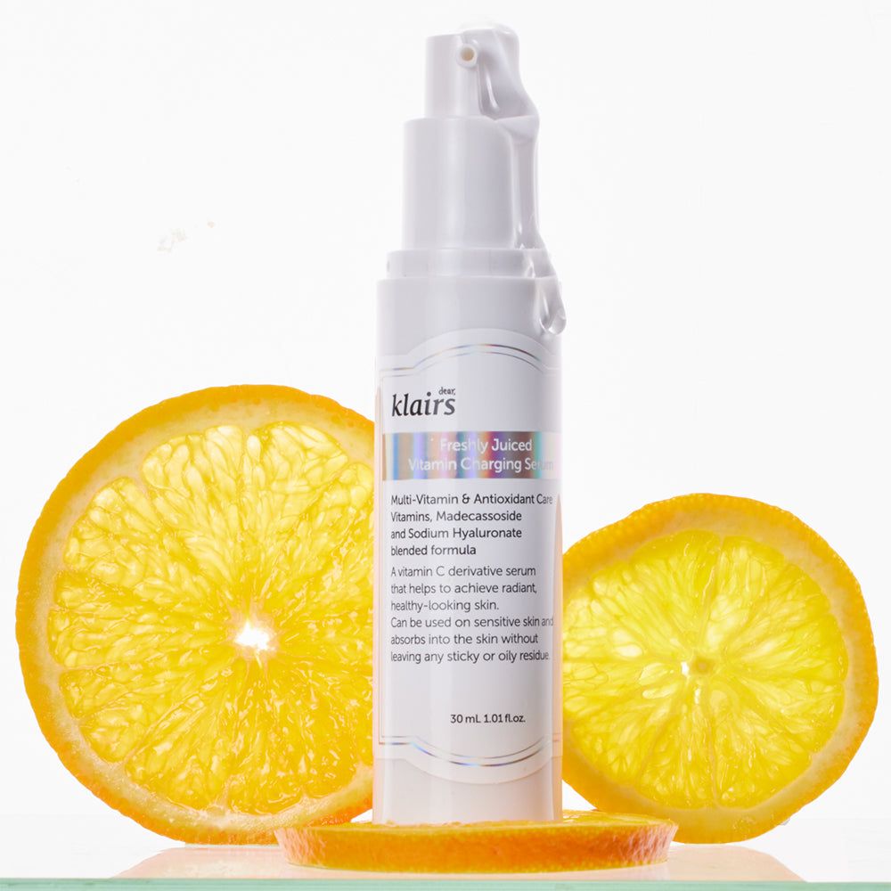 Flacone di siero bianco con erogatore a spruzzo, circondato da fette di arancia. Testo: klairs, Freshly Juiced Charging Serum. 30 ml.