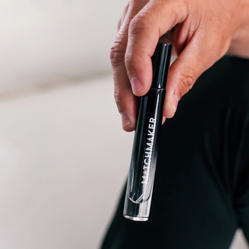 Mano che tiene un flacone nero con scritta bianca MATCHMAKER. Il flacone è riempito a metà.