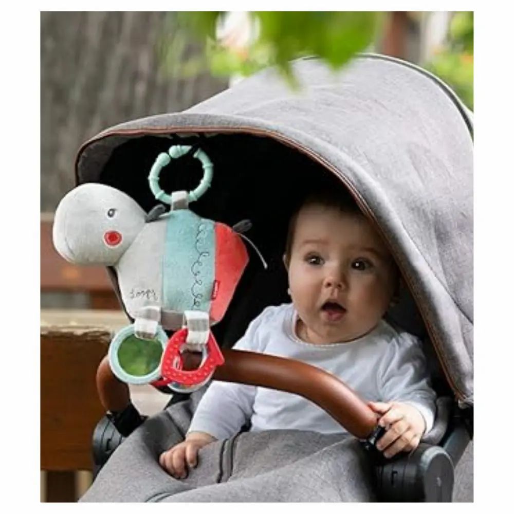 Bambino in passeggino con ippopotamo di stoffa. Il giocattolo è appeso.