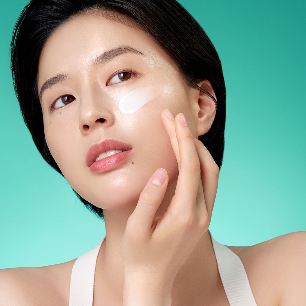 Una donna applica la crema Purito Mighty Bamboo Panthenol sulla guancia.