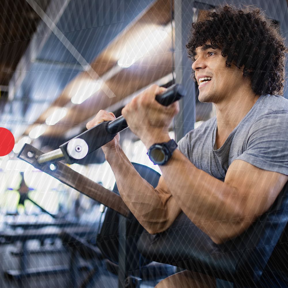 Uomo che si allena in palestra. Si allena con una macchina. Indossa uno smartwatch.