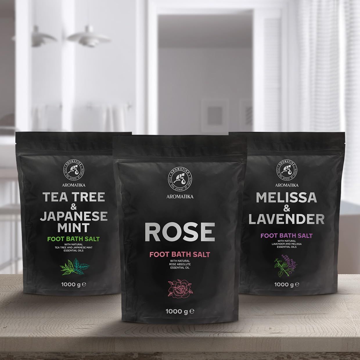 Tre sacchetti neri di sali da bagno per i piedi. Scritte: Tea Tree & Menta giapponese, Rosa, Melissa & Lavanda. Logo: Aromatica. 1000 g.