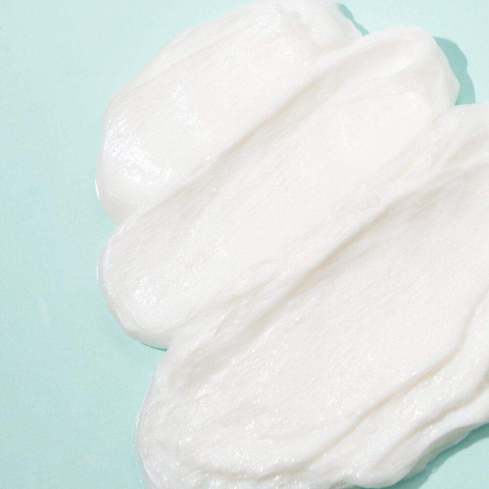 Tre strisce di crema bianca su sfondo azzurro. Visibile la consistenza della crema.