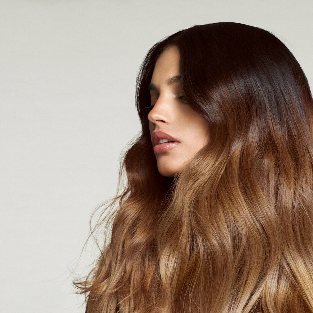 Donna con capelli castani che cadono a onde. Capelli tinti di marrone chiaro.