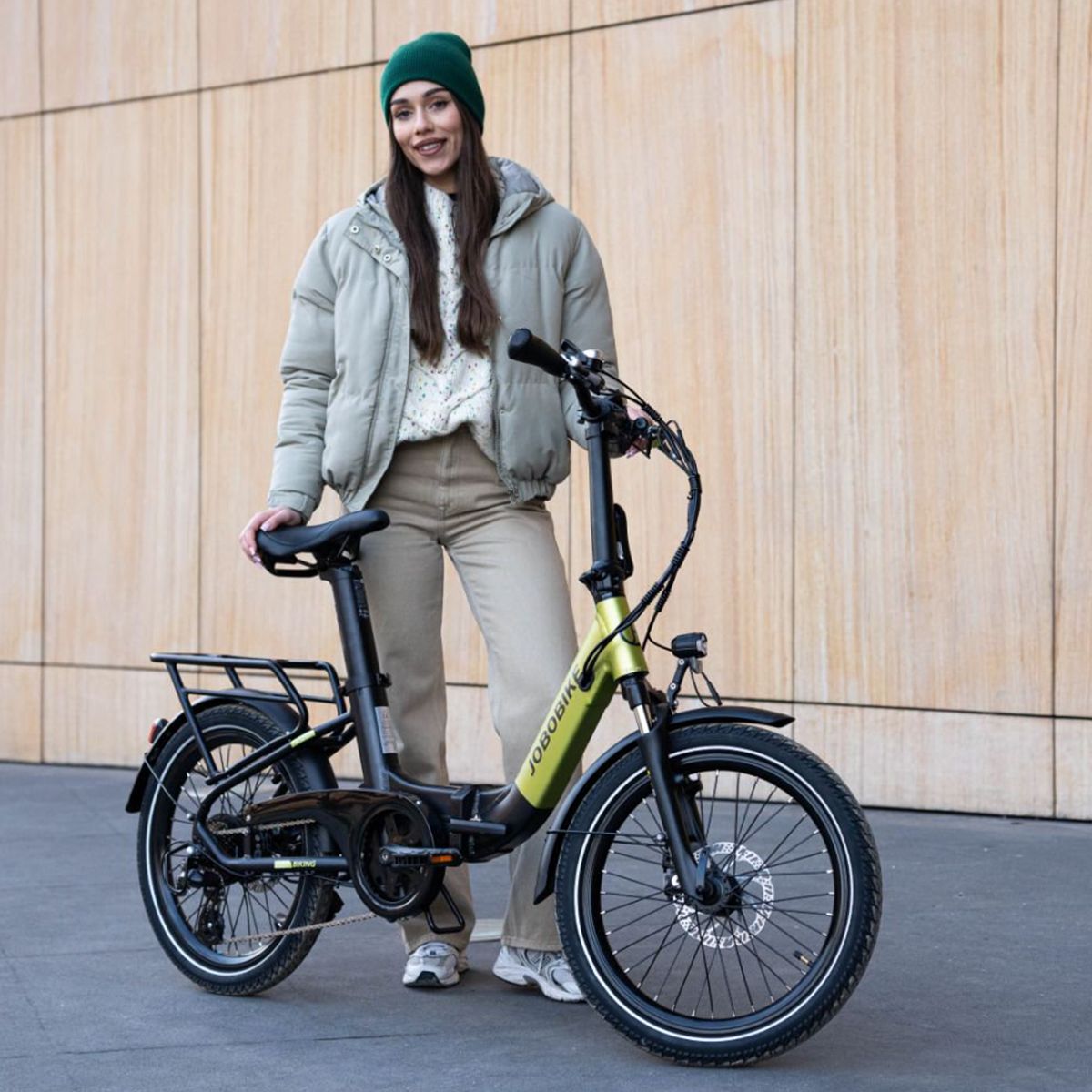 E-bike pieghevole verde-nero. Logo JOBOBIKE. Portapacchi, parafanghi. Persona accanto alla bici.