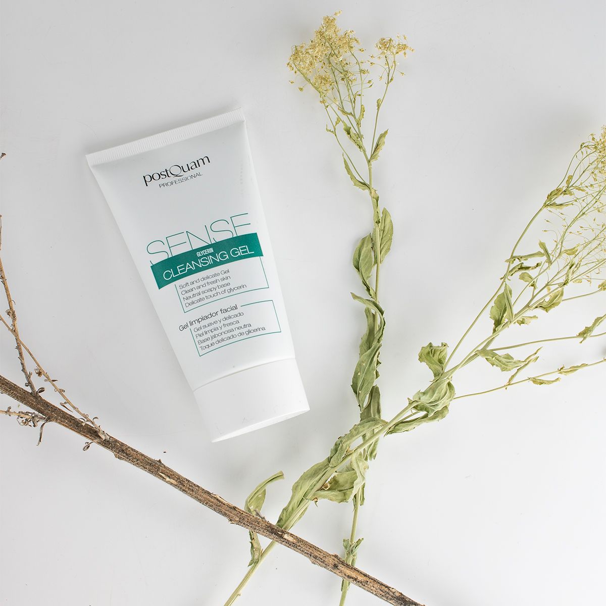 Tubo bianco con etichetta verde. Scritta: PostQuam, Sense Cleansing Gel. Su sfondo bianco con rami.