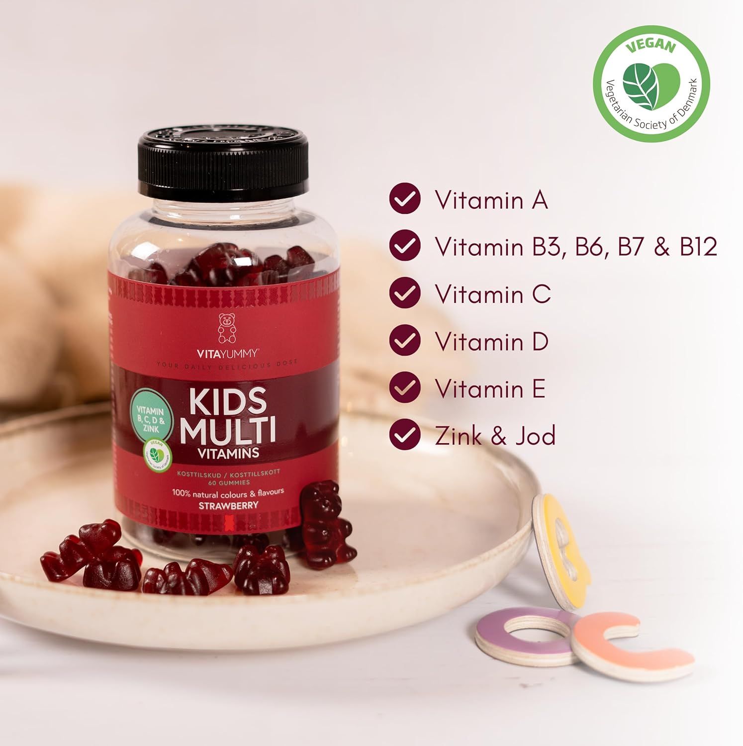 Bottiglia di orsetti gommosi rossi. Scritta: KIDS MULTI VITAMINS. Contiene vitamine A, B3, B6, B7, B12, C, D, E, zinco e iodio. Vegano.