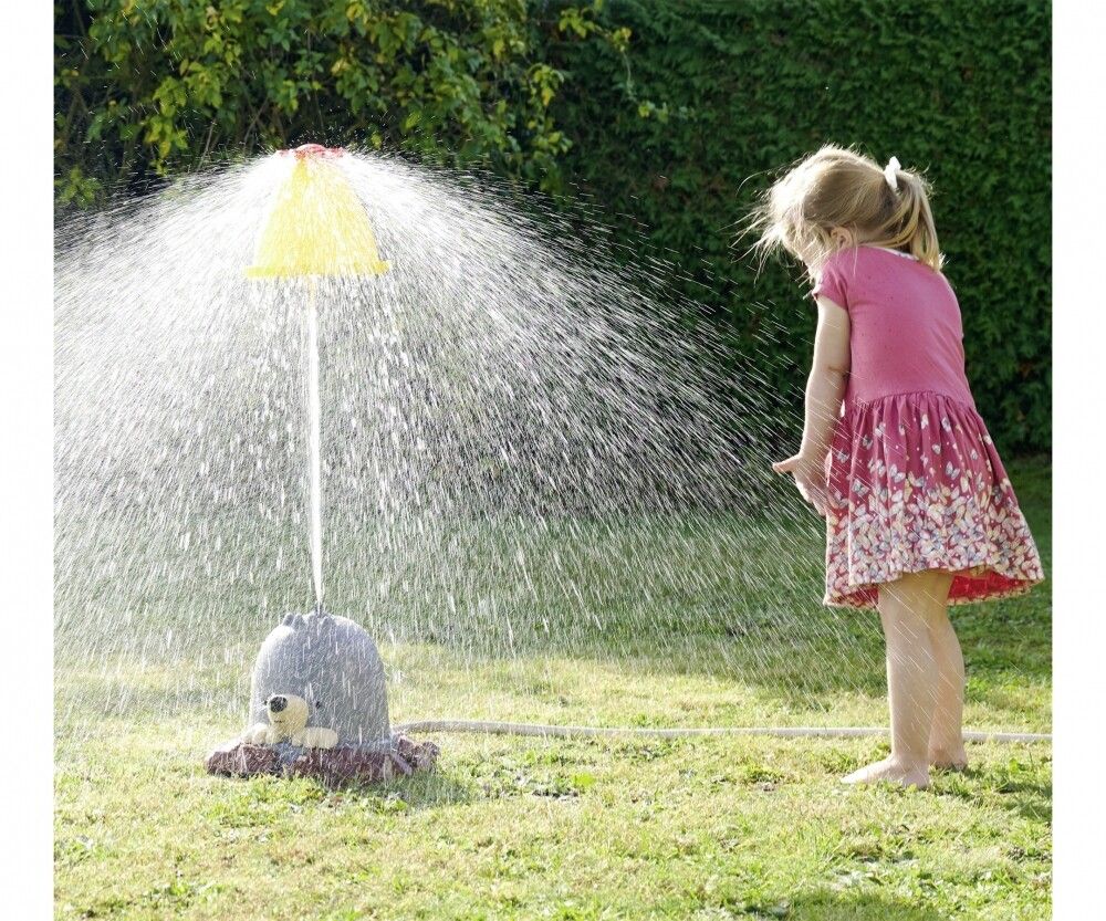 Giocattolo acquatico con ombrello giallo, bambino in giardino. Getto d'acqua dall'ombrello. Bambino sull'erba.