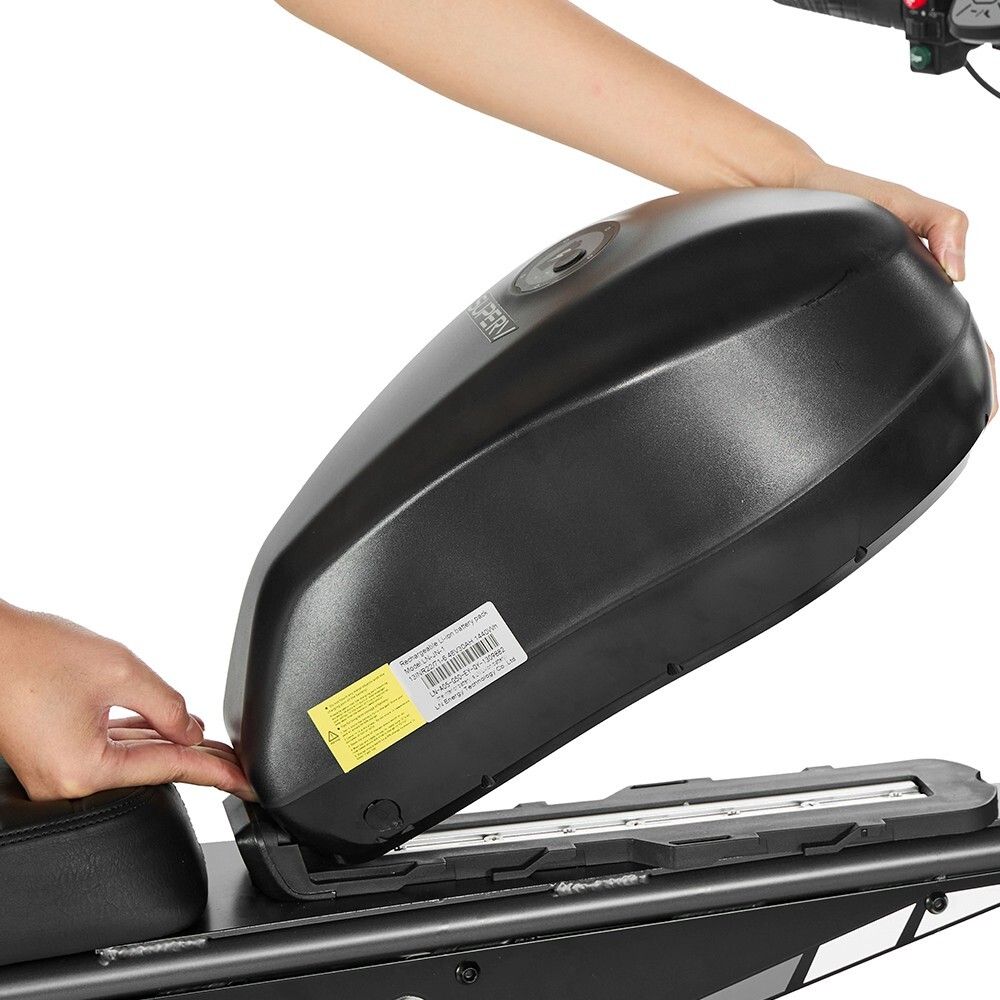 Persona che posiziona una batteria nera sulla dirt bike. Telaio nero, batteria con adesivi. Mani nell'immagine.