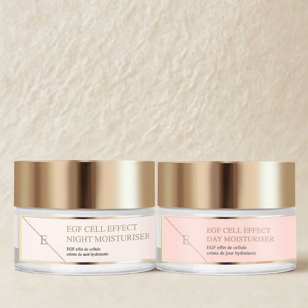 Due vasetti di crema idratante giorno e notte con coperchi dorati ed etichette rosa. I prodotti sono affiancati, su sfondo color crema.