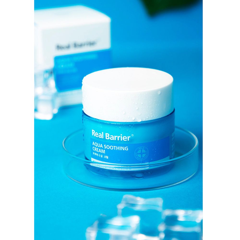 Vasetto di crema blu su piastra di vetro, confezione accanto. Scritta: Real Barrier Aqua Soothing Cream.
