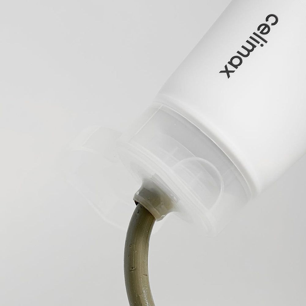 Primo piano dell'apertura di un tubo da cui fuoriesce una maschera all'argilla grigio-verde.