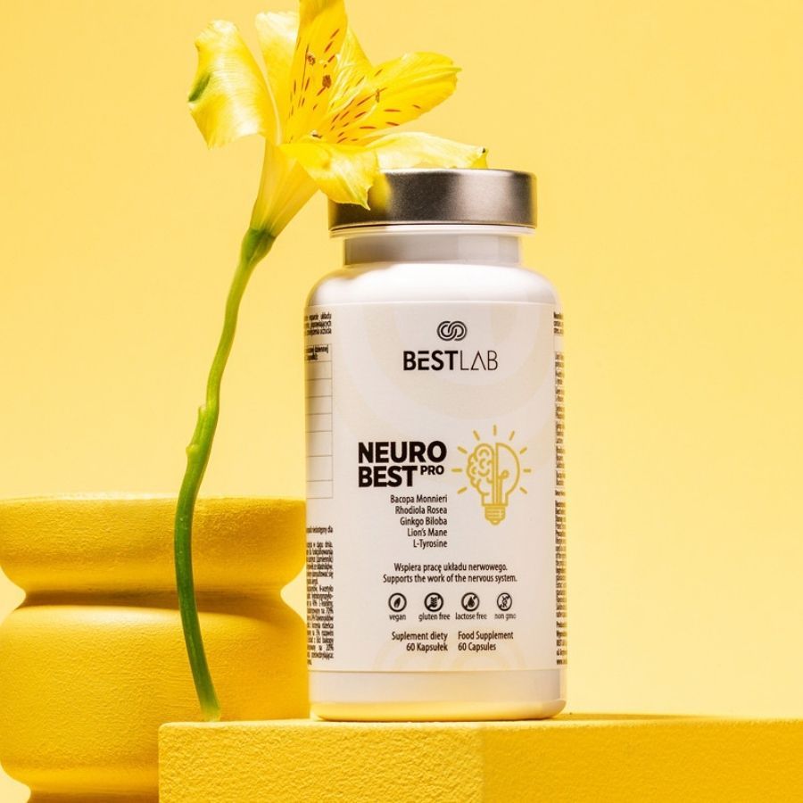 Flacone bianco con capsule vicino a fiore giallo e vaso. Scritta: BEST LAB NEURO BEST PRO. 60 capsule.