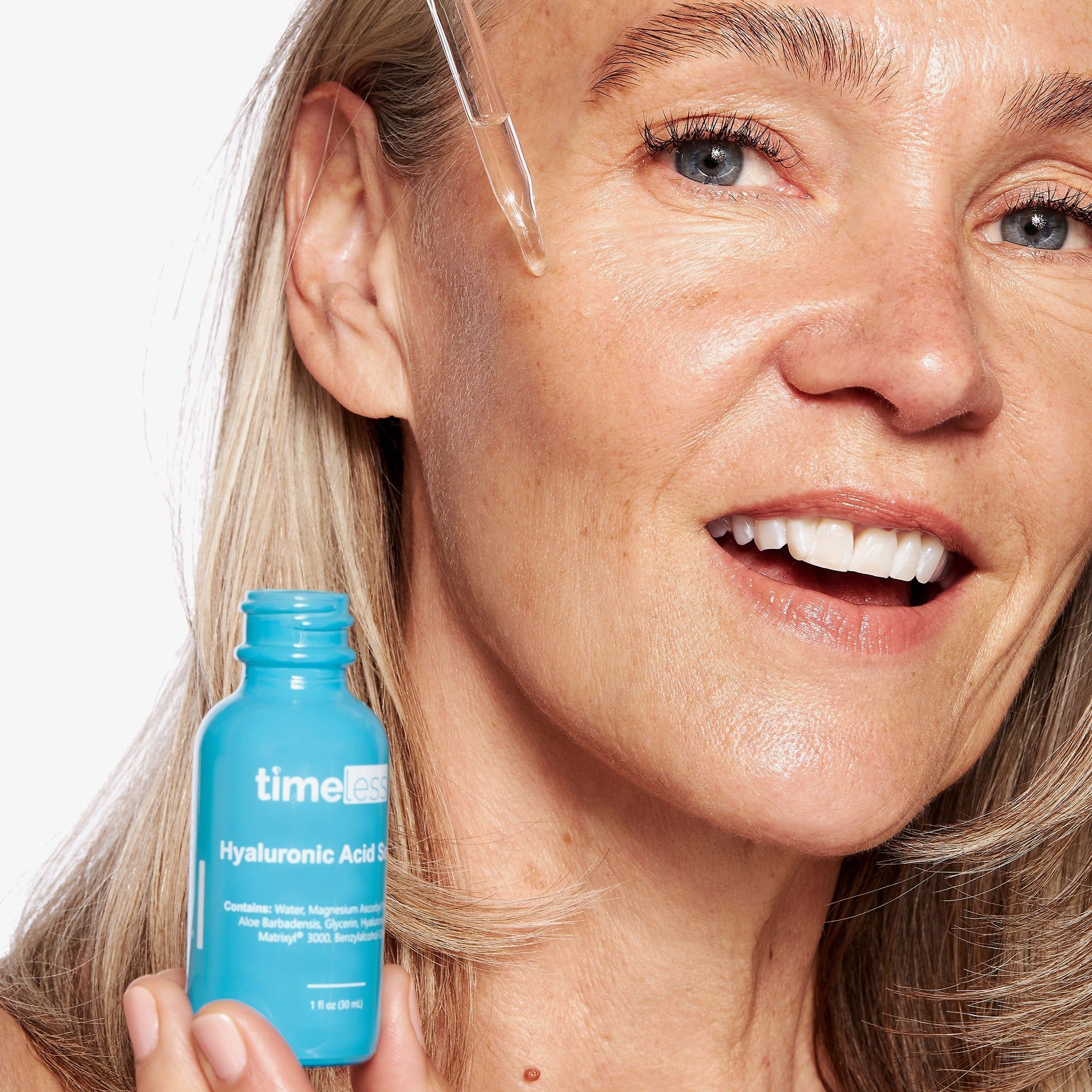 Donna con flacone di siero. Applica il siero. Scritta: Timeless Hyaluronic Acid Serum.
