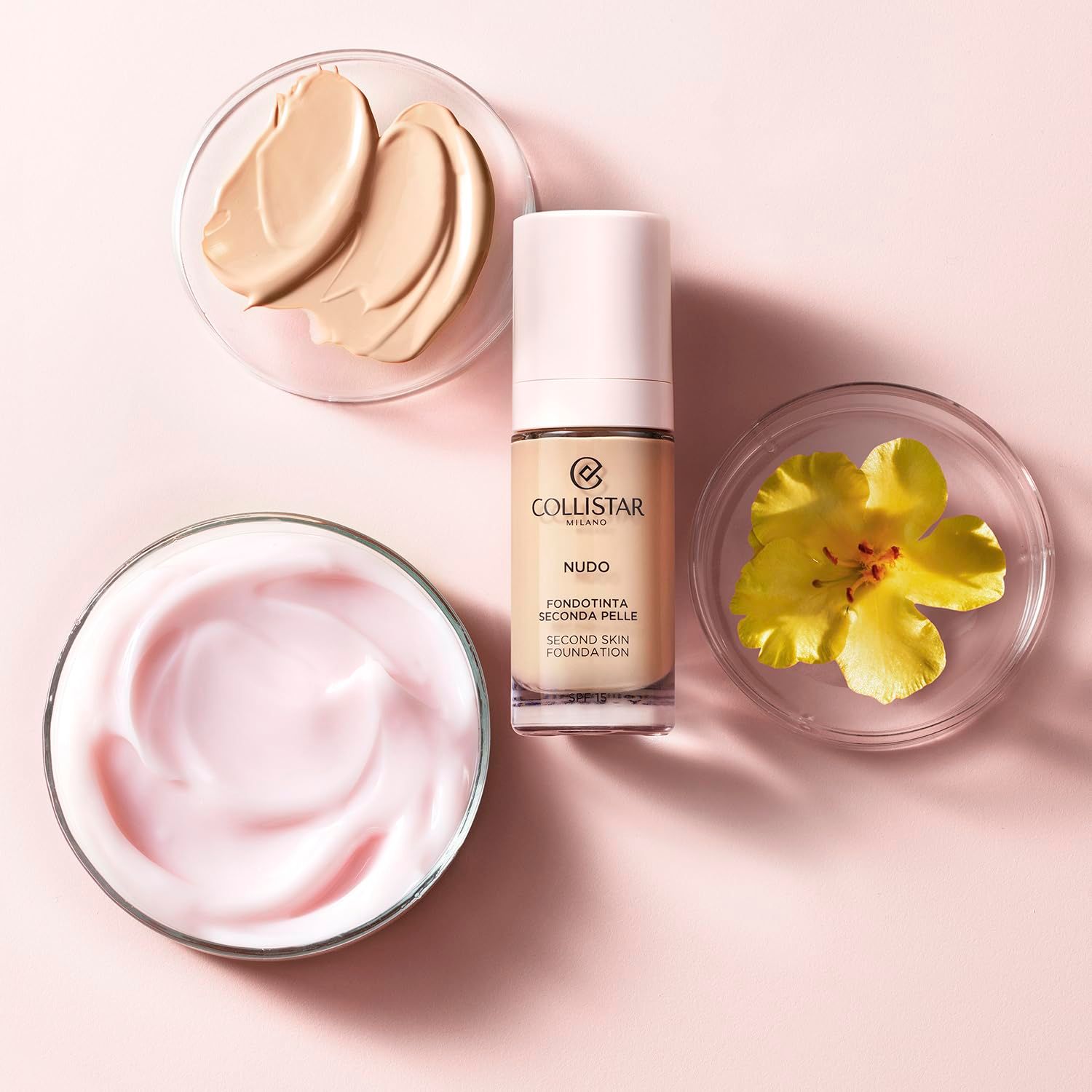 Flacone di fondotinta, creme e fiore. Marchio Collistar. NUDO Fondotinta Seconda Pelle. Creme in ciotole. Fiore giallo.