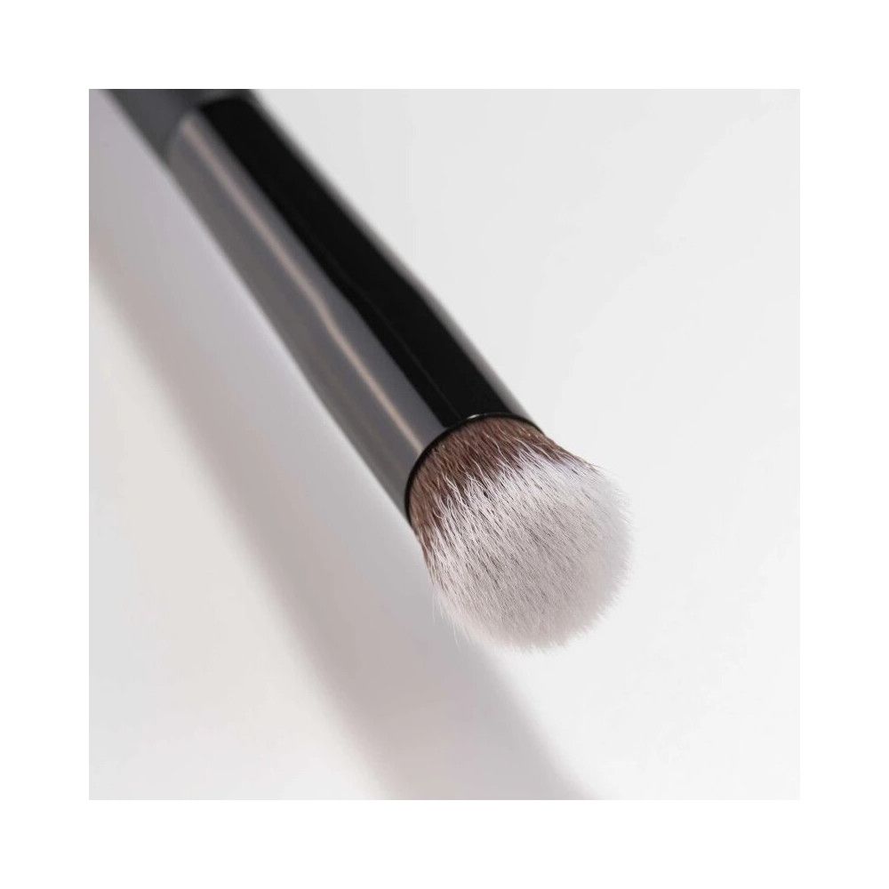 Pennello con manico nero e testina chiara. Primo piano, obliquo.