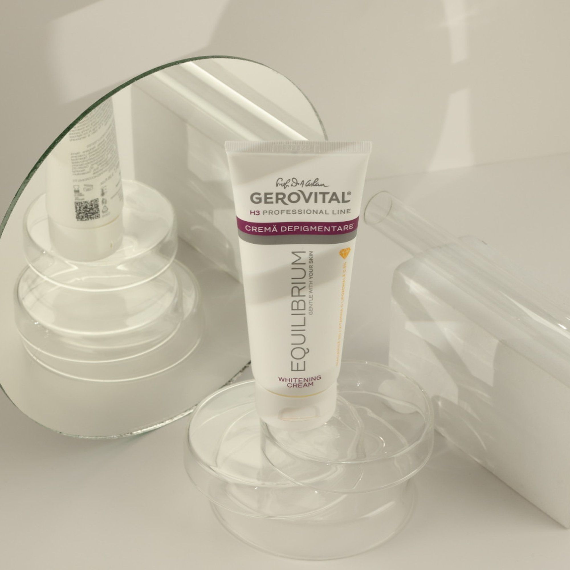 Tubo bianco su piedistalli trasparenti davanti a specchio. Scritta: Gerovital H3 Professional Line, Créma Depigmentare, Equilibrium Whitening Cream.