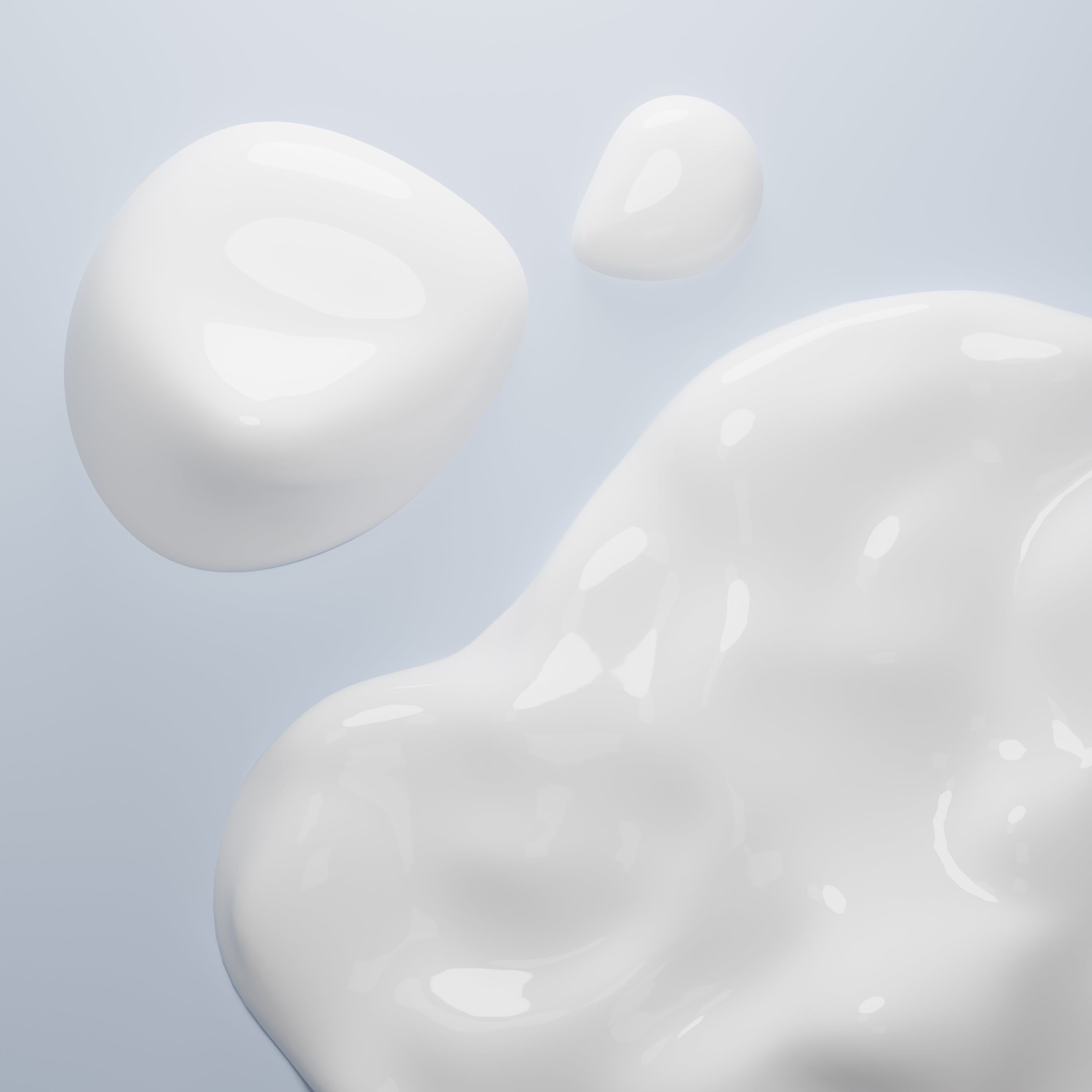 Primo piano di gocce di crema bianca a forma di goccia su sfondo chiaro.