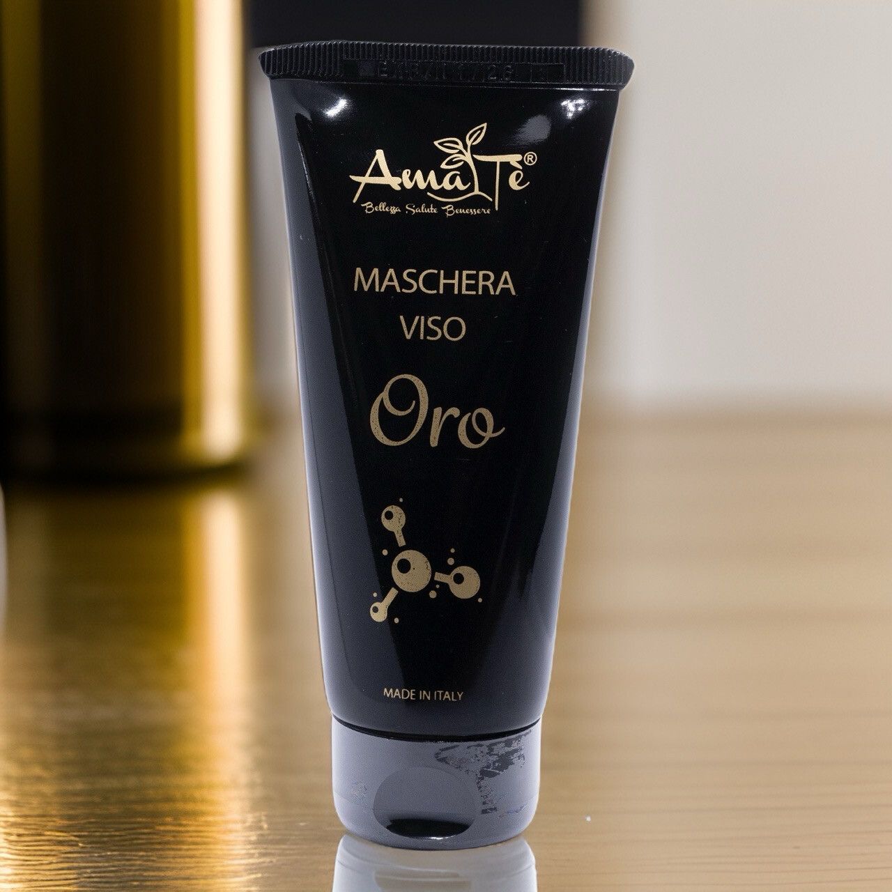Tubo nero con testo dorato. Scritta: Amatè, Maschera Viso, Oro. Prodotto in Italia. Su sfondo chiaro.