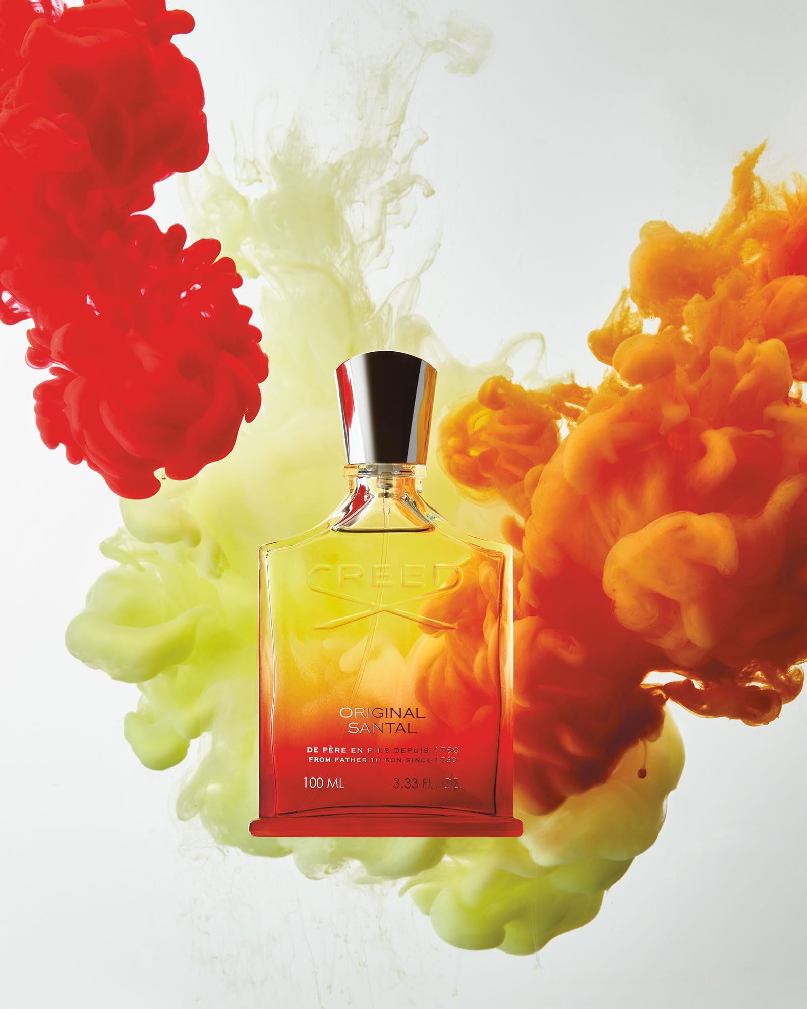 Flacone di profumo sfumato davanti a nuvole di fumo colorate. Scritta: CREED ORIGINAL SANTAL.