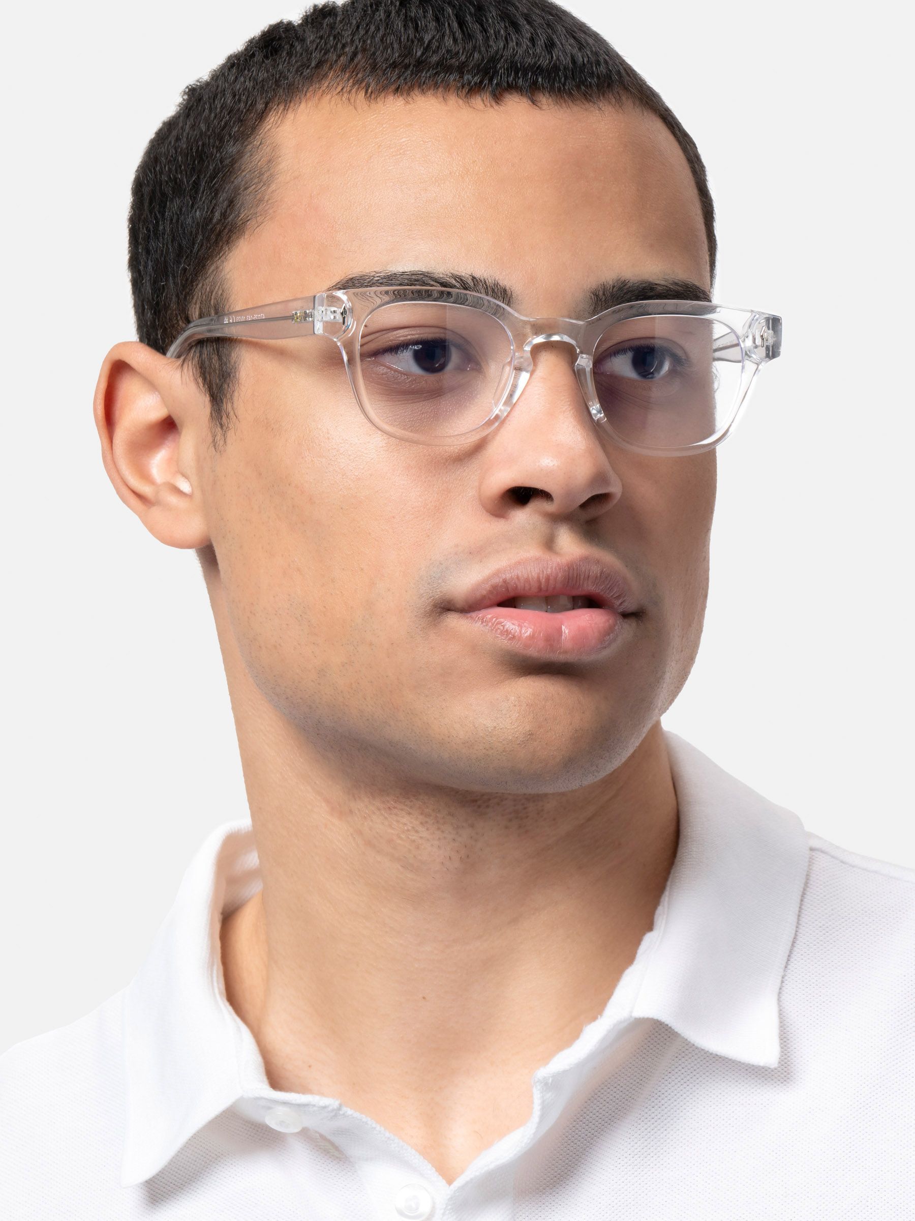 Uomo con occhiali trasparenti. Gli occhiali hanno lenti rotonde e montatura trasparente. Camicia bianca.