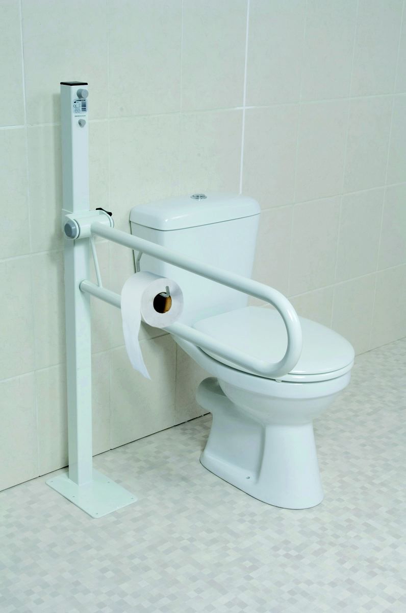 Maniglione bianco pieghevole con portarotolo integrato, accanto a un WC. Montato su un supporto verticale.