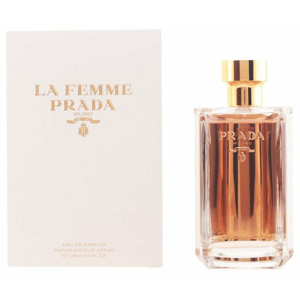 Flacone di profumo accanto a confezione bianca. Sulla confezione 'La Femme Prada'. Flacone con tappo dorato.