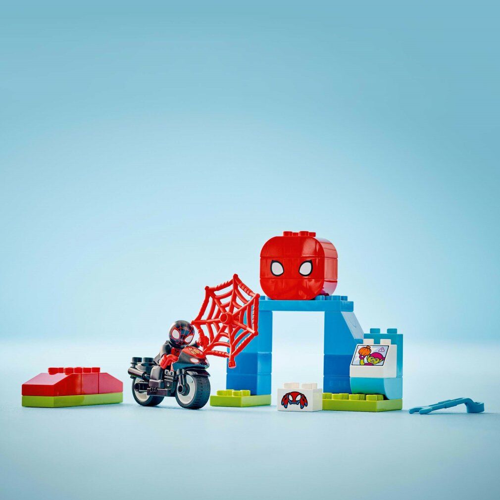 Set LEGO Duplo. Moto, personaggio, edificio, ragnatela, attrezzo. Su sfondo blu.