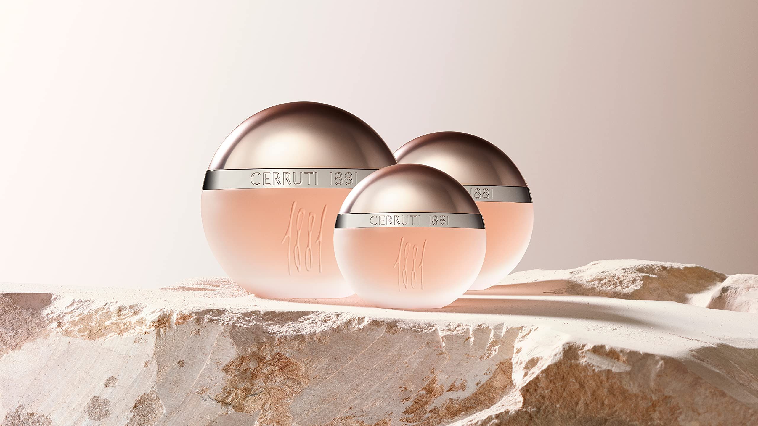 Tre flaconi su una superficie. Flaconi con tappi argentati e scritta Cerruti 1881. Liquido rosa.